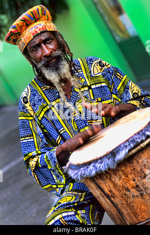 Colorato Rasta reggae giamaicano attore sul tamburo in costume al porto di St John Antigua Foto Stock