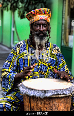 Colorato Rasta reggae giamaicano attore sul tamburo in costume al porto di St John Antigua Foto Stock