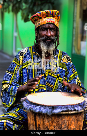 Colorato Rasta reggae giamaicano attore sul tamburo in costume al porto di St John Antigua Foto Stock