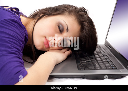 Ritratto di una stanca brunette dormire sul suo computer portatile Foto Stock