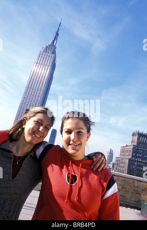 Twin giovani donne in posa di fronte di Empire State Building, NYC Foto Stock