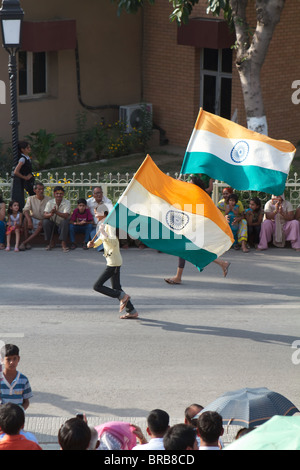 Gli indiani le donne in esecuzione con bandiere indiano a Wagha Border cerimonia Foto Stock