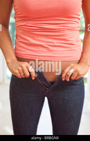 Donna che lottano per zip pantaloni stretti Foto Stock