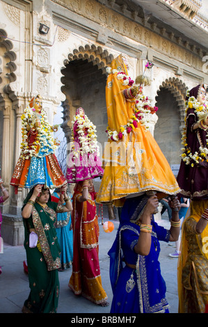 Sari clad le donne che trasportano gli idoli presso il Festival di Mewar in Udaipur, Rajasthan, India Foto Stock