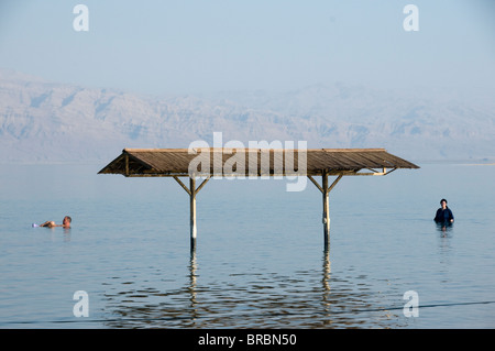 L'uomo flottante e religiosa ebraica donna completamente vestito, balneazione nel Mar Morto, Israele Foto Stock