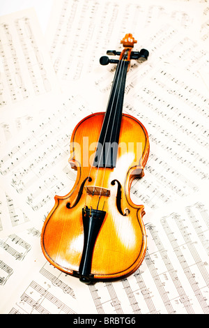 Il legno vecchio violino giacente su note musicali closeup Foto Stock