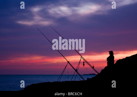 Un pescatore stagliano contro un Cielo di tramonto a Ogmore dal mare sulla Glamorgan Heritage Coast. Foto Stock