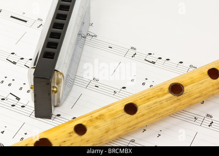 Blues harmonica e tubo di legno che giace sulla musica notesheet Foto Stock