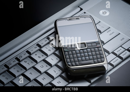 Smart telefono cellulare su un laptop di argento Foto Stock