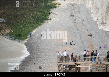 Bianco gesso scogliere a Birling Gap, East Sussex, Inghilterra, Regno Unito con gli escursionisti sulla piattaforma di accesso alla spiaggia Foto Stock