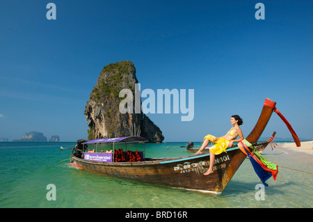 Donna relax su una barca dalla lunga coda al Porto di Laem Phra Nang Beach, Krabi, Thailandia Foto Stock