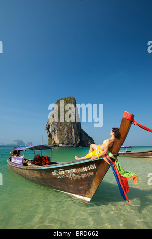 Donna relax su una barca dalla lunga coda al Porto di Laem Phra Nang Beach, Krabi, Thailandia Foto Stock