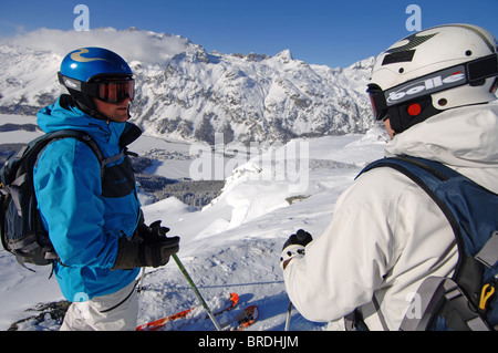 Due maschi gli sciatori in piedi in un scenic, località alpine in attesa di iniziare la loro corsa Foto Stock