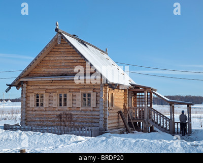 Un uomo alla ricerca nel campo della neve all'ingresso del registro tradizionale casa Russo Foto Stock
