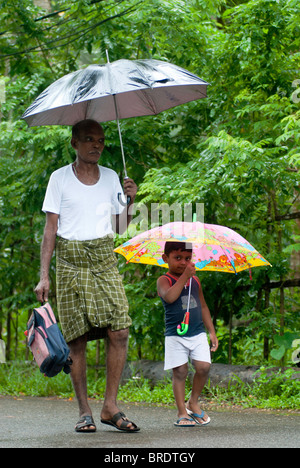 Un vecchio uomo è il suo modo per far cadere il suo nipote a scuola durante il monsone; giornata piovosa a Alappuzha; Alleppey, Kuttanad, Kerala. Foto Stock