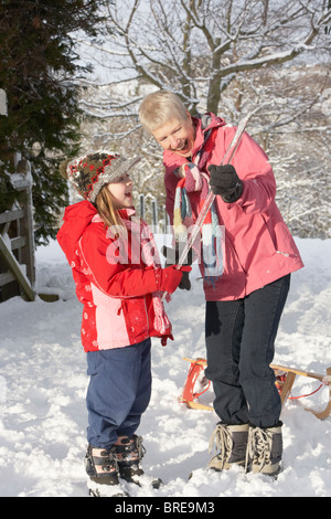 Giovane ragazza che mostra la nonna ghiacciolo nel paesaggio innevato Foto Stock