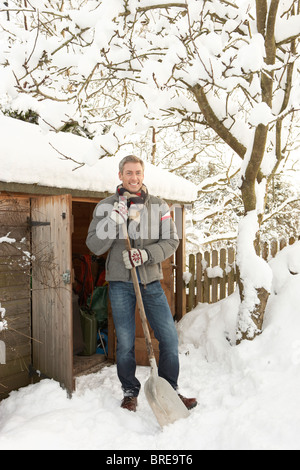 Uomo di mezza età la rimozione di neve dal percorso di archivio in legno Foto Stock