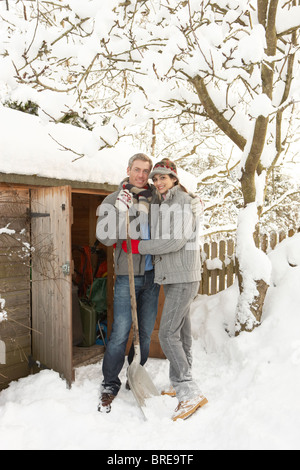 Coppia giovane la rimozione di neve dal percorso di archivio in legno Foto Stock