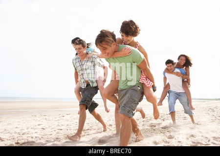 Gruppo di amici che corre lungo la spiaggia insieme Foto Stock