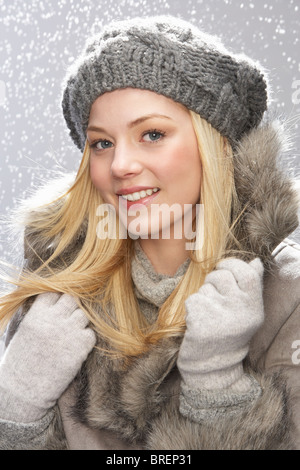 Moda ragazza adolescente che indossa il cappuccio e pelliccia in studio con la neve Foto Stock