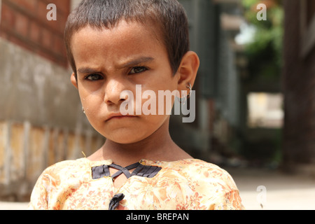 Un rifugiato Cute girl scowls presso la fotocamera in un campo di rifugiati di configurazione per le vittime delle inondazioni in Shikarpur, Pakistan Foto Stock