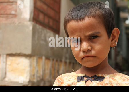 Un rifugiato Cute girl scowls presso la fotocamera in un campo di rifugiati di configurazione per le vittime delle inondazioni in Shikarpur, Pakistan Foto Stock