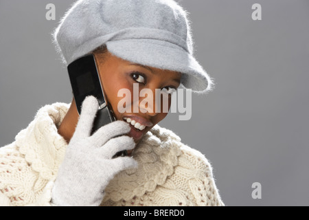 Moda donna che indossa la maglieria e cappuccio in Studio utilizzando il telefono cellulare Foto Stock