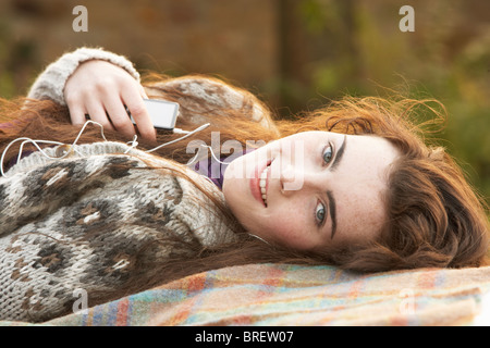 Ritratto di bella ragazza adolescente all'aperto ascoltando MP3 Player nel paesaggio autunnale Foto Stock