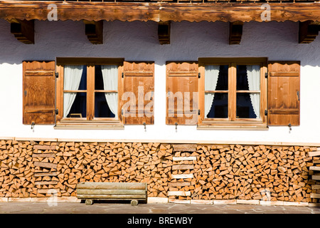 Pila di legno nella parte anteriore di una farm house finestra, Baviera, Germania, Europa Foto Stock