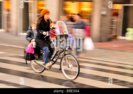 Ciclista con i bambini nel centro della città di Amsterdam, Olanda, Paesi Bassi, Europa Foto Stock