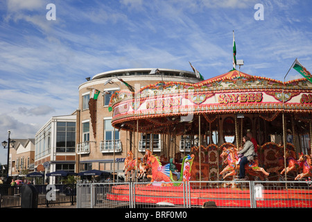 La Baia di Cardiff (Bae Caerdydd), Glamorgan, South Wales, Regno Unito, Europa. Persone su cavalli sulla fiera carosello ride sul lungomare Foto Stock