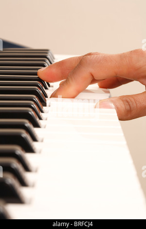 Una mano si gioca su una tastiera di pianoforte Foto Stock