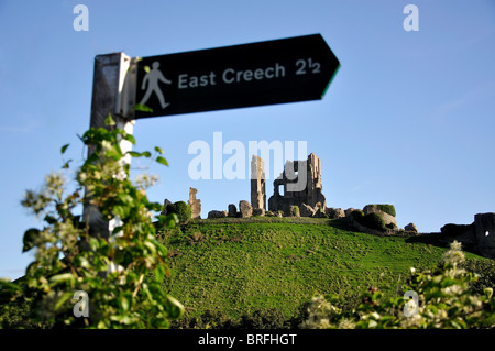 Rovine di Corfe Castle al tramonto e sentiero a piedi segno, Corfe Castle, Isle of Purbeck, Dorset, England, Regno Unito Foto Stock