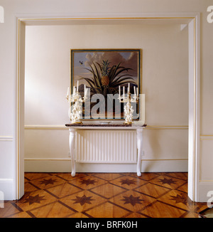 Grande immagine sulla parete sopra la tabella della console con antichi candelabri in sala tradizionale con stampata pavimenti in legno Foto Stock