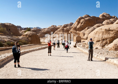 I turisti a camminare verso il Siq, canyon ingresso alle antiche rocce scolpite città Petra, Giordania. Foto Stock
