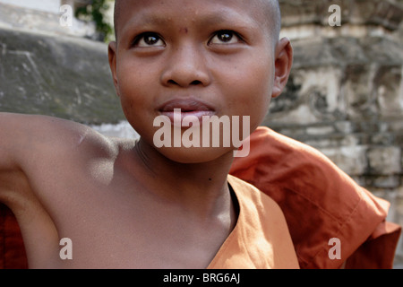 Un giovane debuttante Khmer monaco buddista mette sulla sua tunica arancione a un tempio in Phnom Penh Cambogia. Foto Stock