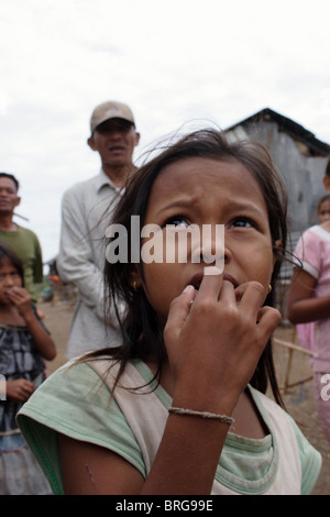 Una giovane ragazza che vive in un squatter di baraccopoli in Kampong Cham, Cambogia, indica che lei è affamato. Foto Stock