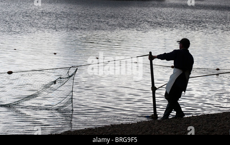 Salmone Tradizionale netsman sul fiume Tweed portando in rete Foto Stock