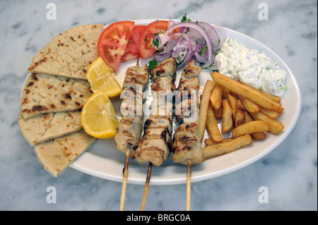 Souvlaki greco. Spiedino di pollo su una piastra con patate, insalata e Tzatziki, Grecia. Foto Stock