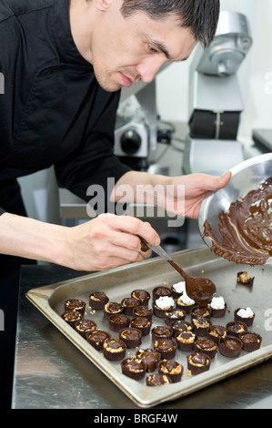 Maschio caucasico chef rende i dolci al cioccolato secondo la propria ricetta Foto Stock