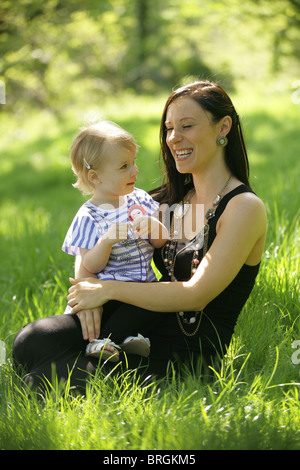 Madre seduta con il suo bambino al di fuori in una giornata di sole. Foto Stock