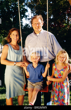 Famiglia di quattro persone sorridenti alla camera di Backyard, 1997 Foto Stock