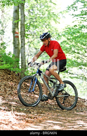 Senior sportivo con mountain bike nei boschi Foto Stock