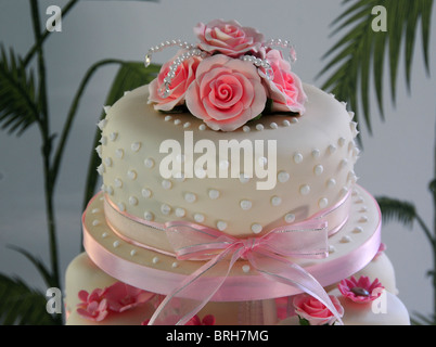 Il livello più alto di una rosa e bianco torta di nozze fatta con tazza di torte e decorata con un nastro rosa e rose. Dorset, Regno Unito 2009 Foto Stock