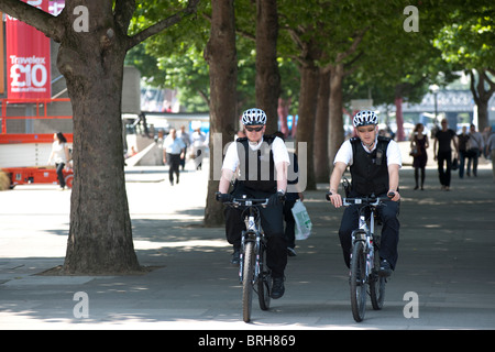 Metropolitan due poliziotti in bicicletta lungo la riva sud del fiume Tamigi nel centro di Londra. Foto Stock