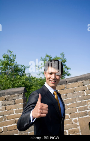 Imprenditore sulla Grande Muraglia dando pollice in alto Foto Stock