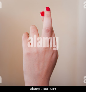 Donna dito mano attraversato, rosso smalto per unghie. Foto Stock