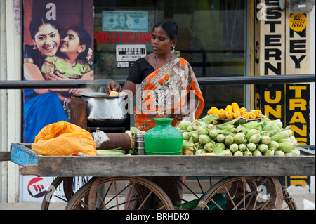 India donna street venditore a vendere cotta sulla pannocchia di mais. Puttaparthi, Andhra Pradesh, India Foto Stock