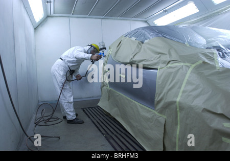 Un uomo in una cabina di verniciatura a spruzzo in cui si lavora su una riparazione auto REGNO UNITO Foto Stock