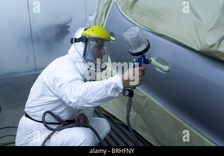 Un uomo in una cabina di verniciatura a spruzzo in cui si lavora su una riparazione auto REGNO UNITO Foto Stock